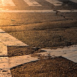 Arrows on a road point straight ahead and to the right with a sunset in the background